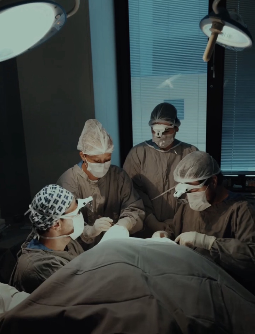 Equipe do Fellowship durante uma cirurgia de transplante capilar, paciente coberto por campos